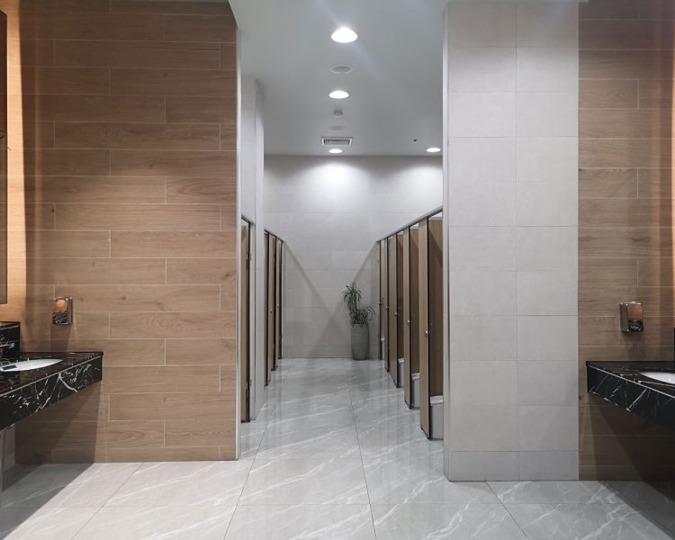 Modern Commercial Restroom Lighting Design The interior of a sleek, modern public restroom featuring recessed ceiling lights, marble countertops, and tiled walls.